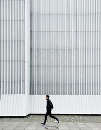 Full length of a man walking on footpath against building