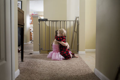 Side view of siblings embracing on carpet at home