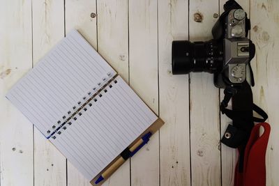 Directly above shot of camera and diary on wooden table