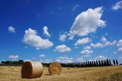 Hay bales on field against sky