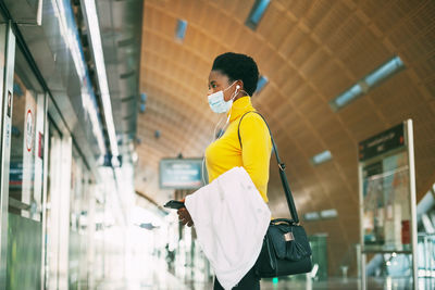 An african girl in a protective mask waits for the arrival of the subway 