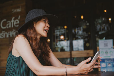 Portrait of young woman using mobile phone in city