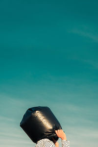 Low angle view of teenage girl with plastic in head against blue sky