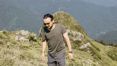 Young man standing against mountain range
