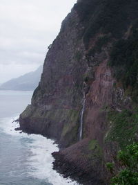 Rock formation by sea against sky