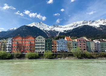 Buildings by mountains against sky during winter