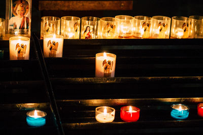 Illuminated tea light candles on table at night