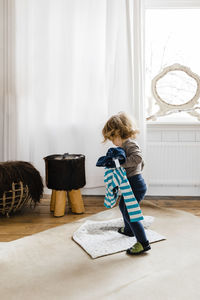 Side view of girl standing by window at home