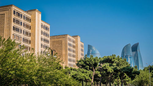 Low angle view of skyscrapers against clear blue sky
