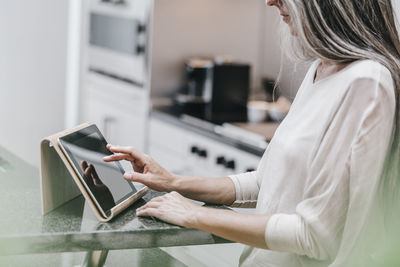 Woman in kitchen using tablet