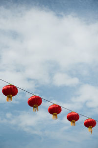 Low angle view of lanterns hanging against cloudy sky