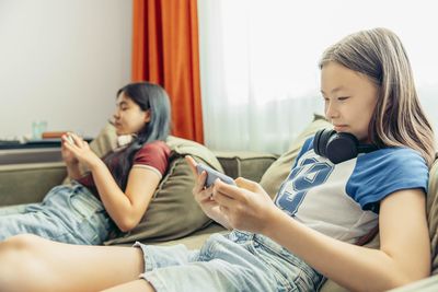 Young woman using mobile phone while sitting at home