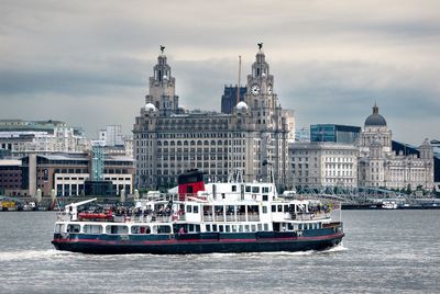 Boats in sea against buildings in city