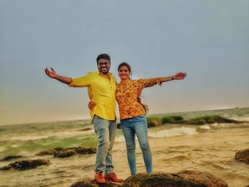 Full length of happy friends standing on land against sky