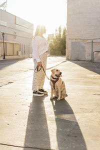 Woman standing with pet dog on sunny day