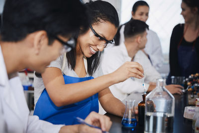 Smiling multi-ethnic students mixing solutions at chemistry laboratory