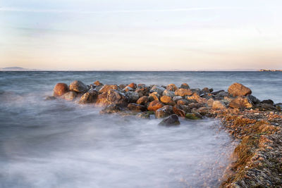 Rocks on sea shore against sky