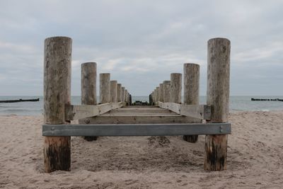 Wooden posts on beach against sky