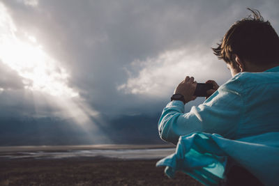 Rear view of boy photographing on beach