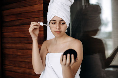 Young girl with towel on her head makes facial treatments. skin care, moisturizing with serum