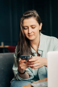 Young woman using mobile phone while sitting at home