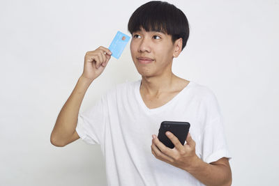 Mid adult man using smart phone against white background