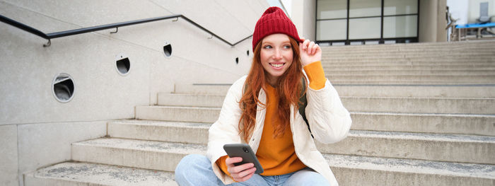 Portrait of young woman standing against wall