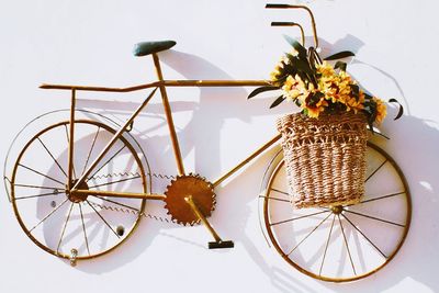 Close-up of bicycle shaped metallic decoration with flowers in basket on wall