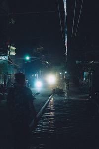 Man on illuminated street in city at night