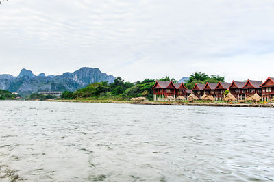 Houses by sea against sky