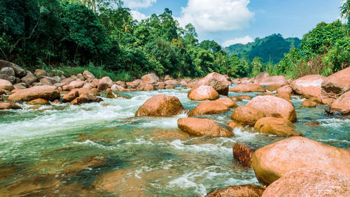 Rocks by river against sky