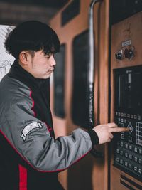 Side view of young man using smart plastic machine 