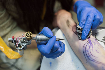 Midsection of artist making tattoo on customer hand