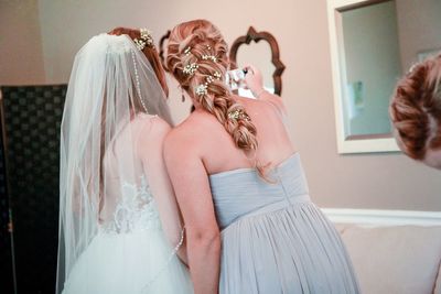 Bride with bridesmaid taking selfie in wedding ceremony