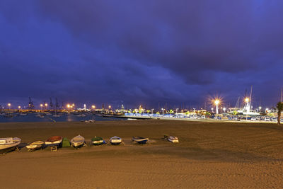 Illuminated city by sea against sky at night