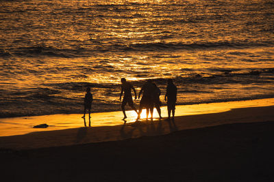 Silhouette people on beach during sunset