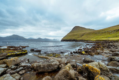 Scenic view of sea and mountains against cloudy sky