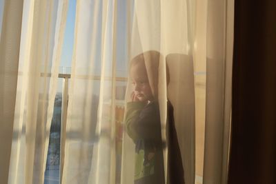 Close-up of boy looking through window