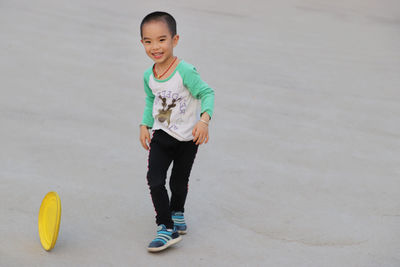 Cheerful boy playing with plastic disc at park