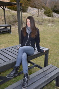 Full length of woman sitting on bench in park