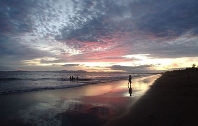 Silhouette person standing on beach against sky during sunset