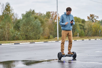 Full length of man using mobile phone on road