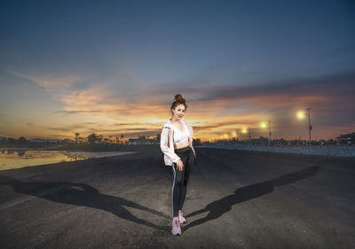 Full length of man standing on road at sunset