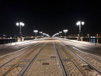 Illuminated railroad tracks in city at night