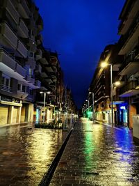 Illuminated street amidst buildings in city at night