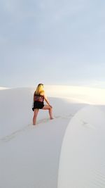 Woman standing on sand at beach against sky