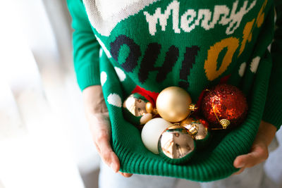 Close-up of woman holding christmas ornaments in sweater