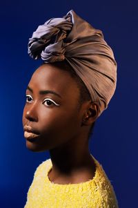 Close-up portrait of young woman against blue background