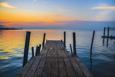 Wooden pier over sea against sky during sunset