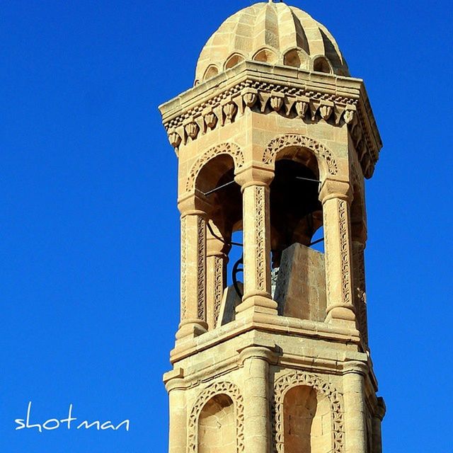 clear sky, low angle view, blue, architecture, religion, building exterior, church, built structure, place of worship, spirituality, clock, clock tower, copy space, tower, cathedral, cross, famous place, high section